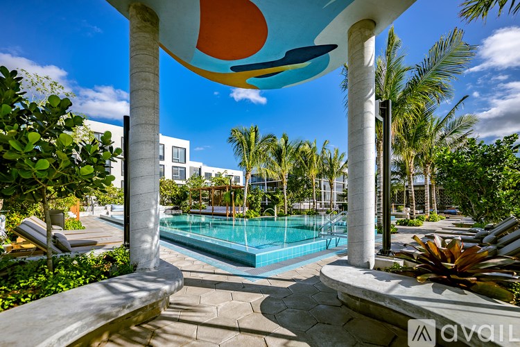 A pool surrounded by palm trees and a white building in the background.