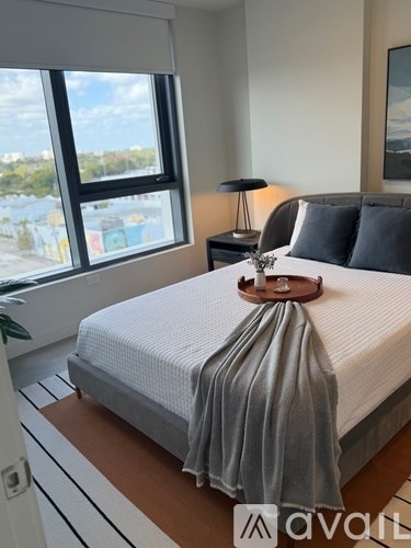 A bedroom with a neatly made bed and a large window.