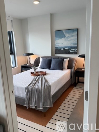 A bedroom with a bed, two lamps, and a painting on the wall.