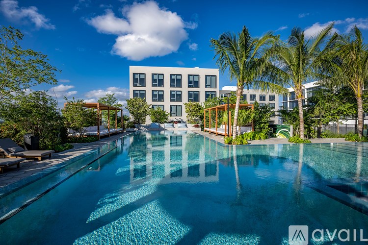 A large swimming pool in front of a modern building with palm trees.