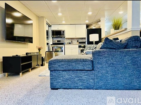 A blue couch is in the foreground of a modern kitchen and living room.