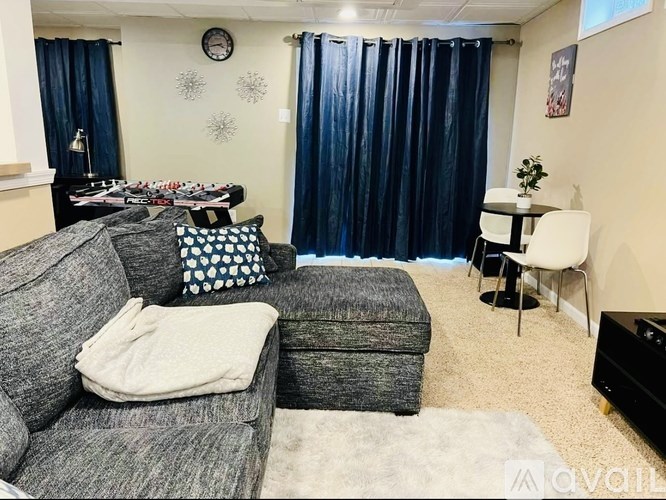 A living room with a grey couch, a white chair, and a black piano.