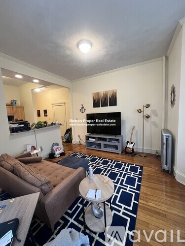 A living room with a brown couch and a blue rug.