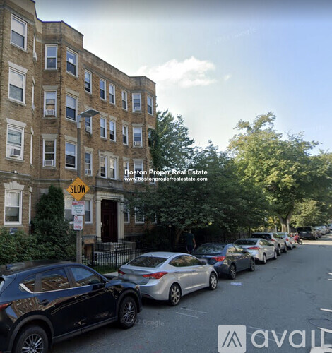 A street view with cars parked on the side and a building in the background.