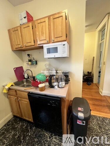 A kitchen with wooden cabinets and a black dishwasher.