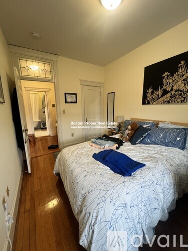 A bedroom with a bed in the center and a painting on the wall.
