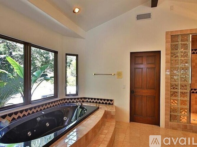 A modern bathroom with a black tub and a wooden door.