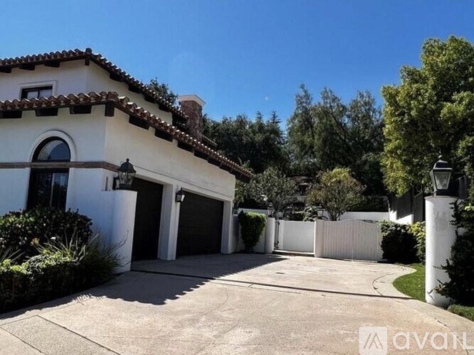 A white house with a brown roof and a driveway in front.