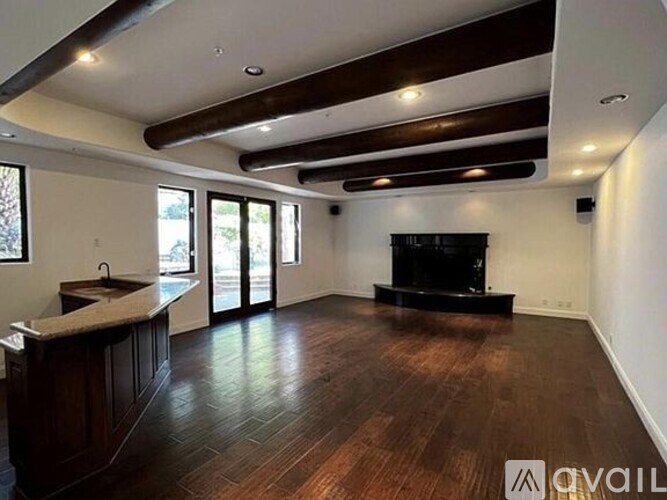 A spacious living room with a dark wood floor and a black fireplace.