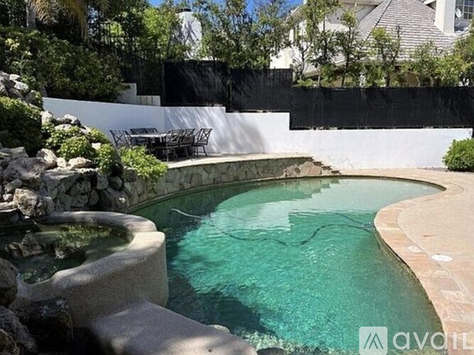 A small pool with a waterfall and a patio area.