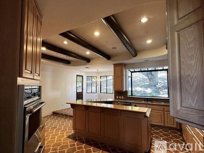 A kitchen with a large island and a window overlooking a snowy landscape.
