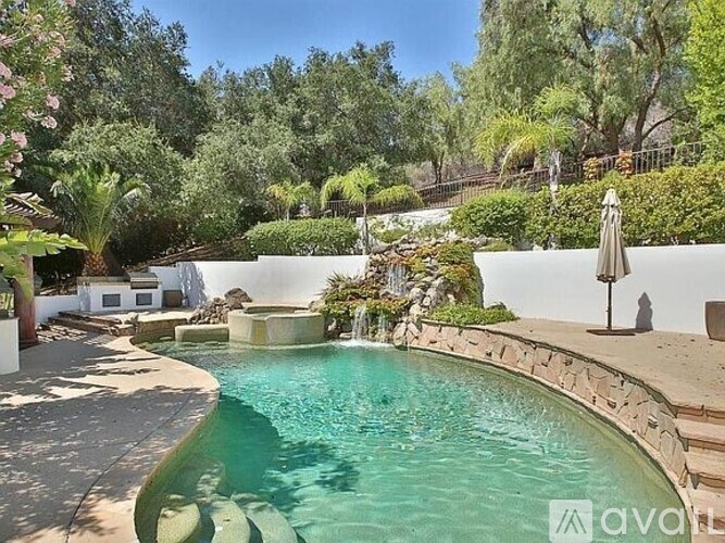 A pool surrounded by a stone wall and trees.