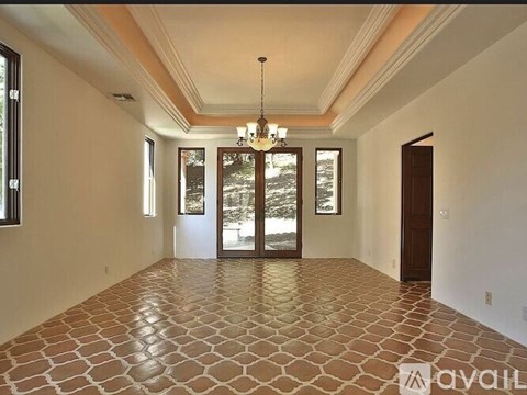 A spacious room with a tiled floor and a chandelier hanging from the ceiling.