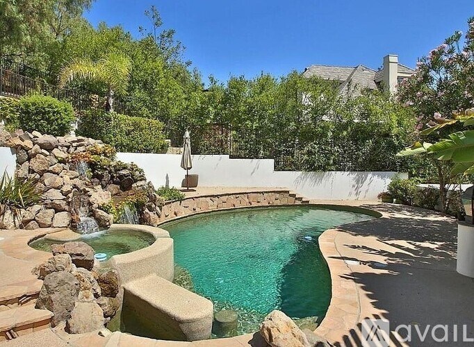A pool with a waterfall and a stone wall.