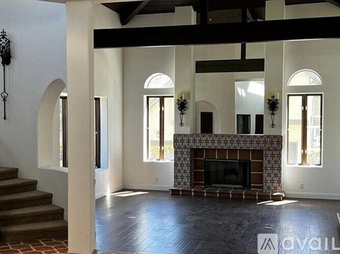 A large, empty room with a fireplace and wooden floors.