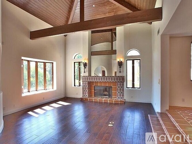 A large, empty room with a fireplace and wooden beams.