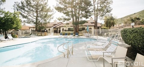 A large outdoor swimming pool surrounded by lounge chairs and trees.