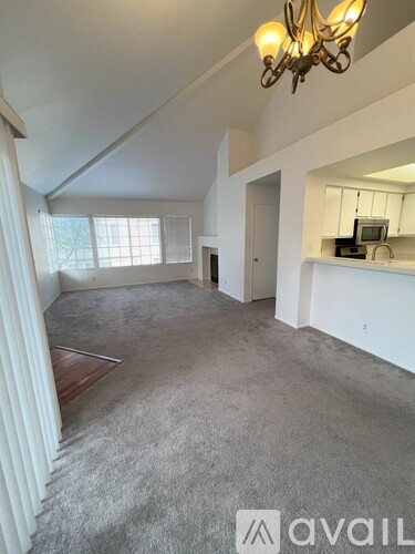 A spacious room with a chandelier and a window.