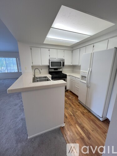 A kitchen with white cabinets and a wooden floor.