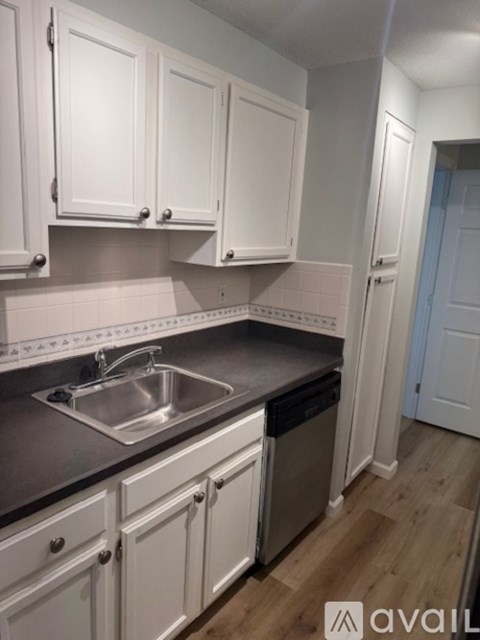 A kitchen with white cabinets and a stainless steel sink.