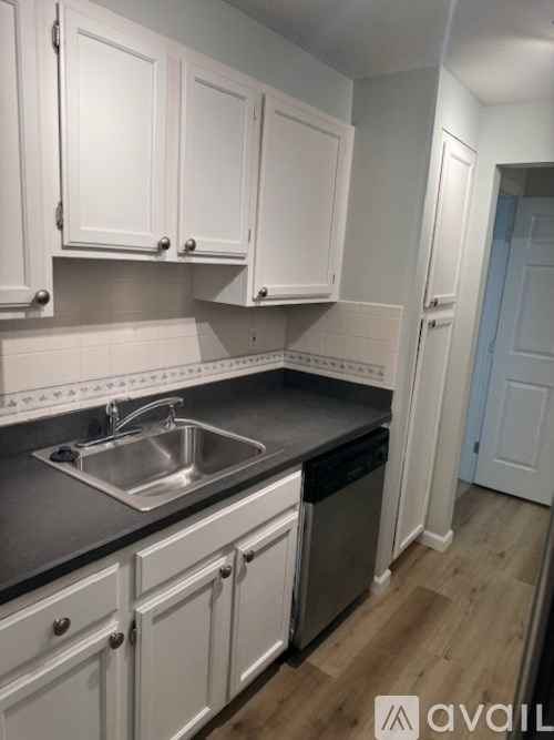 A kitchen with white cabinets and a stainless steel sink.