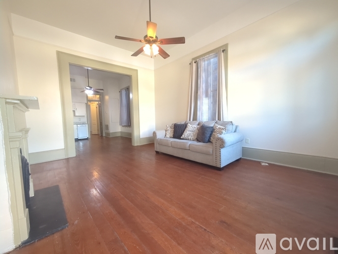 A living room with a white couch and a wooden floor.