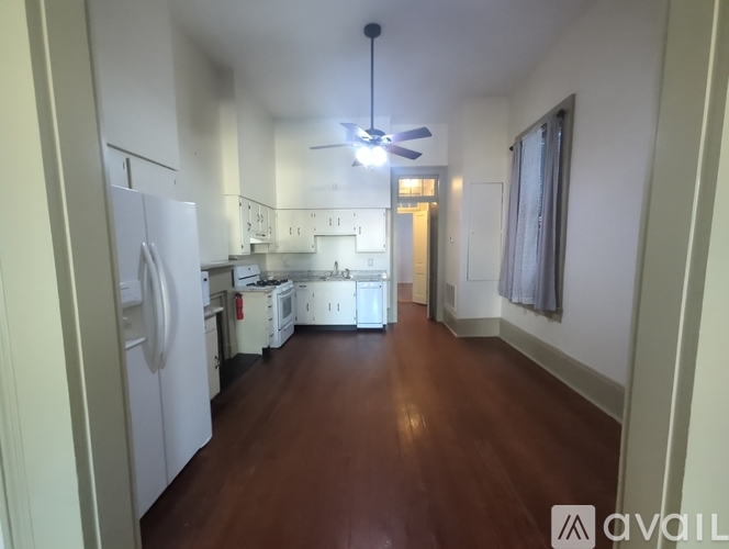 A kitchen with white appliances and wooden floors.