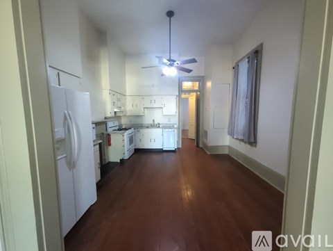 A kitchen with white appliances and wooden floors.