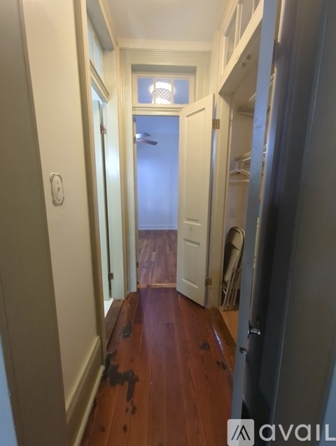 A hallway with a wooden floor and white walls.