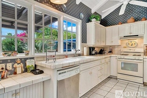A kitchen with white cabinets and a window overlooking a garden.