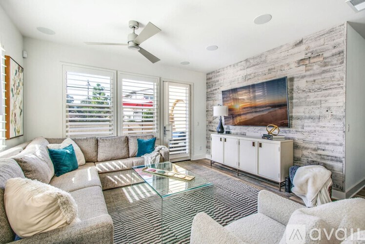 A living room with a grey couch, a glass coffee table, and a white cabinet.