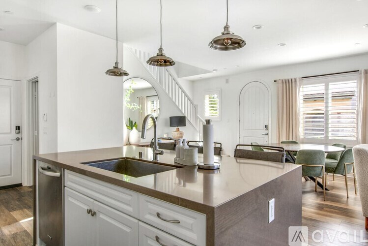A modern kitchen with a dark brown island and white cabinets.
