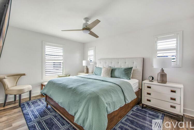 A bedroom with a bed, chair, and ceiling fan.