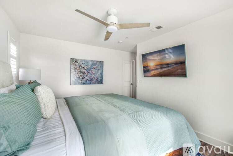 A bedroom with a bed, a ceiling fan, and two pictures on the wall.