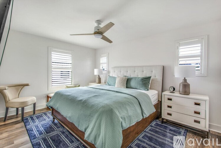 A bedroom with a bed, chair, and ceiling fan.