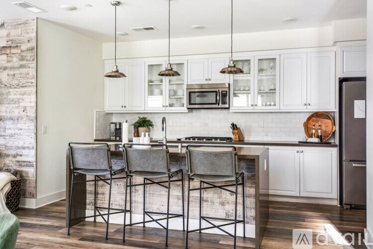A kitchen with white cabinets and a brick wall.