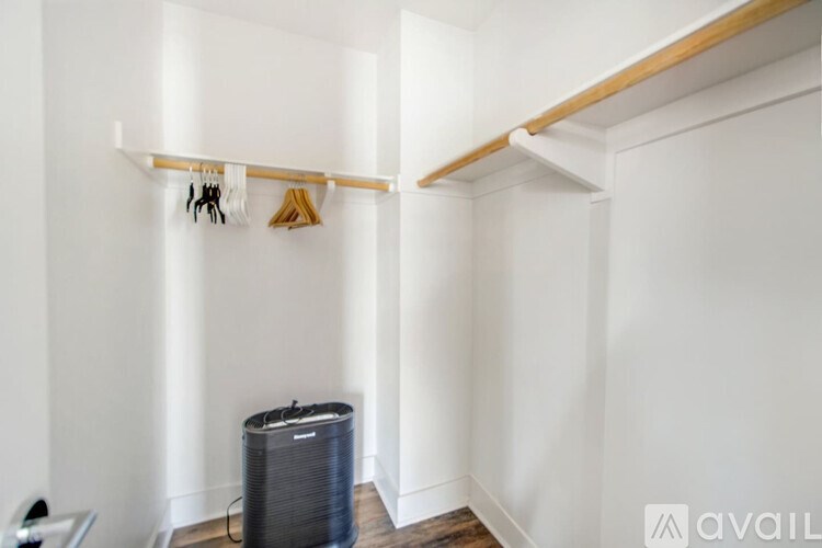 A room with a white wall and a black air conditioner.