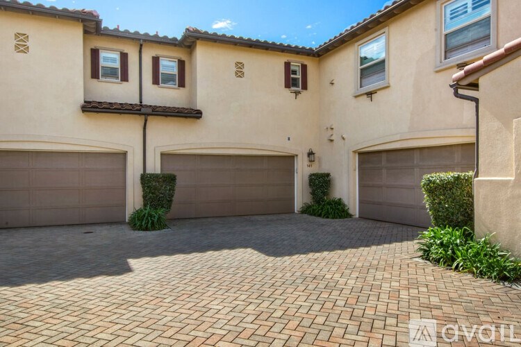 A house with a beige exterior and a brick driveway.