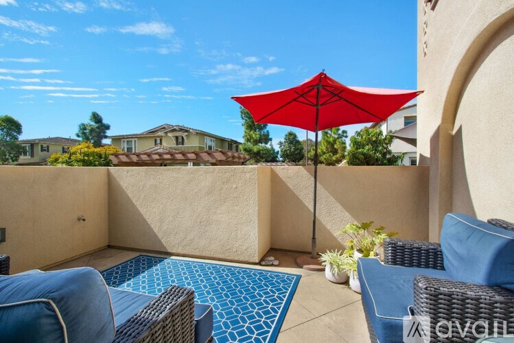 A red umbrella is on a patio with a blue mat.