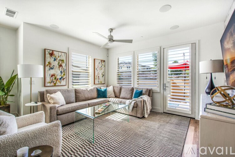 A living room with a glass coffee table and a couch with pillows.