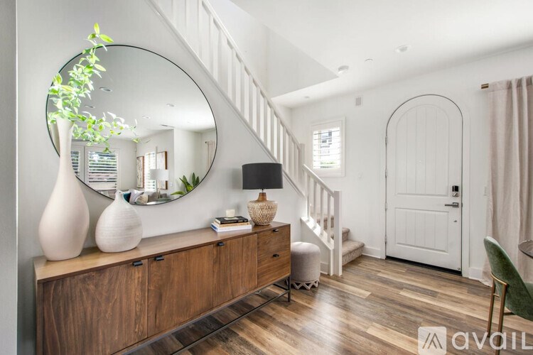 A modern living room with a wooden floor and a white staircase.