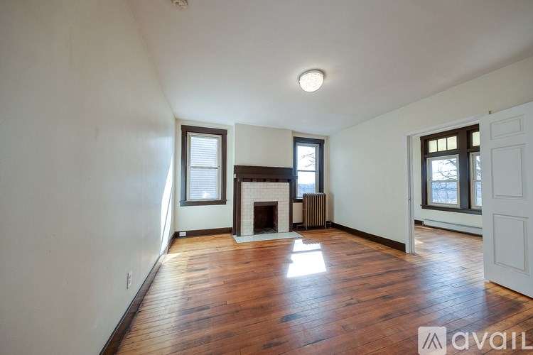 A room with wooden floors and a fireplace with a window on the side.