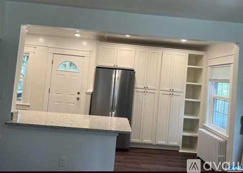 A kitchen with white cabinets and a marble countertop.