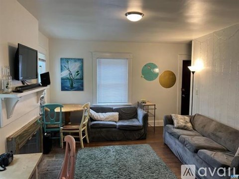 A living room with a grey couch, a green chair, and a television on the wall.