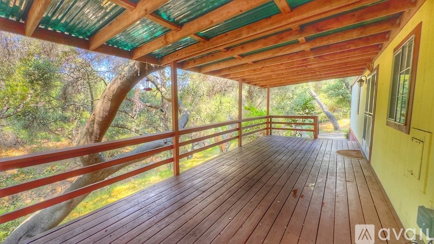 A wooden deck with a red railing and a green roof.