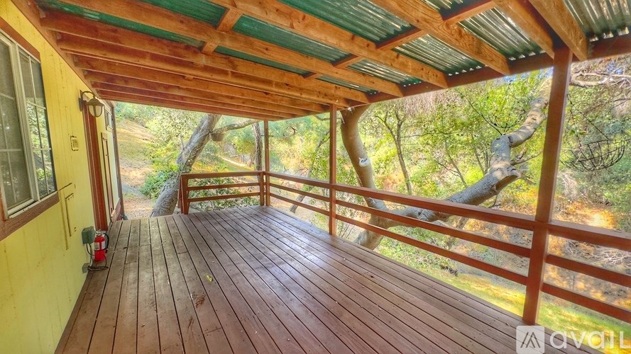 A wooden deck with a metal railing and a green roof.