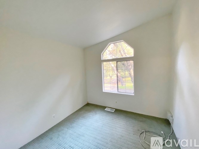 A room with a window and a grey carpet.