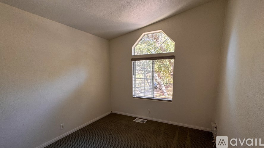 A room with a ceiling fan and two windows.
