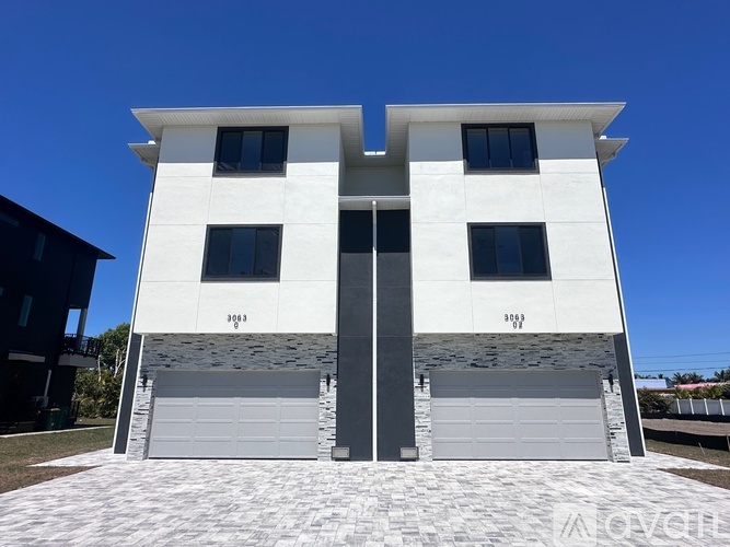 A modern two-story building with a flat roof and garage doors.