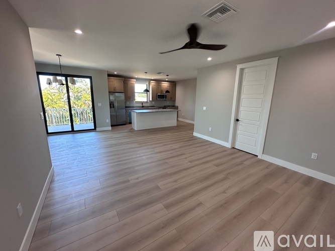 A spacious room with wooden flooring and a ceiling fan.